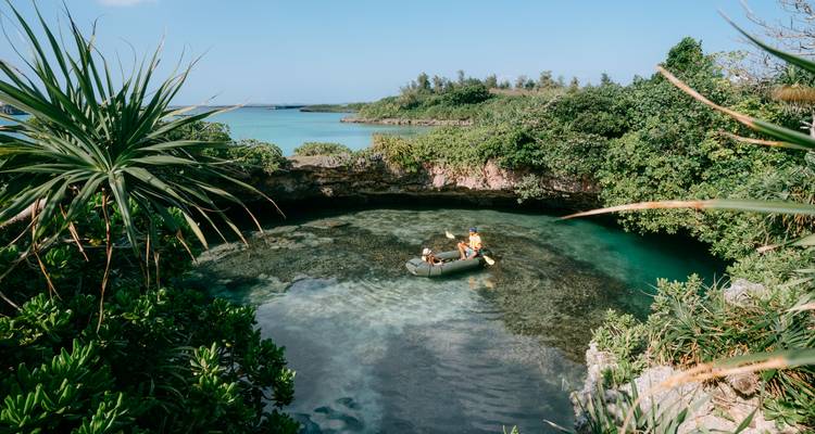 Mensen die in een kleine boot roeien in een weelderige koraaltuin omgeven door groen.