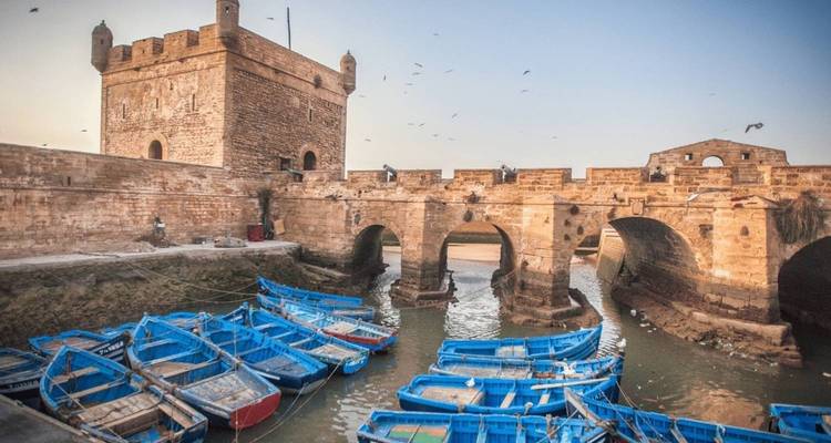 Les anciens murs et remparts de la ville d'Essaouira avec des bateaux au premier plan.