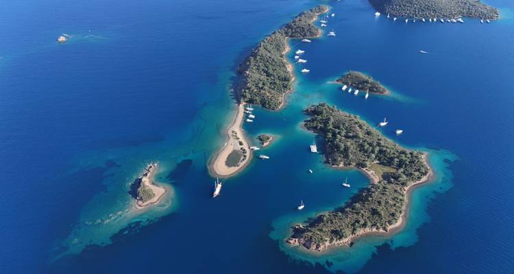 Luftaufnahme von Inseln, umgeben von klarem blauen Wasser und Yachten.