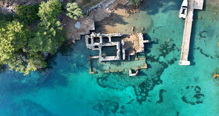 Ruinen unter Wasser, umgeben von türkisfarbenem Wasser in der Nähe eines Docks.