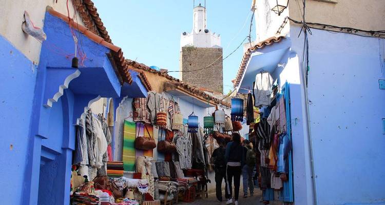 Blue-painted street with shops displaying traditional crafts.