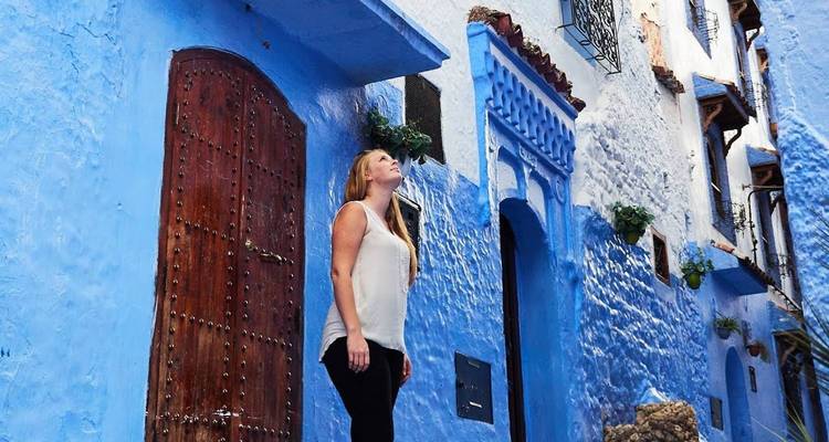 Femme debout dans une ruelle pittoresque aux murs bleus.