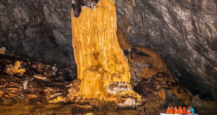 Des gens dans un bateau à l'intérieur d'une grande grotte avec des formations rocheuses.