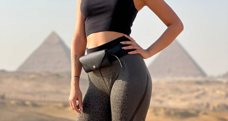 Person posing in front of pyramids wearing casual attire.