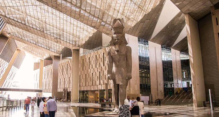 Les visiteurs marchant sous la colossal statue de pharaon à l'intérieur de l'atrium du Grand Musée égyptien aux toits de verre
