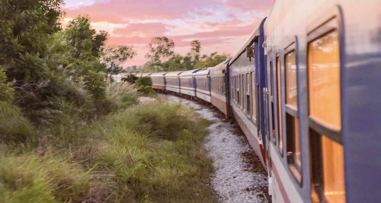 El tren de pasajeros se curva a lo largo del paisaje verde al atardecer