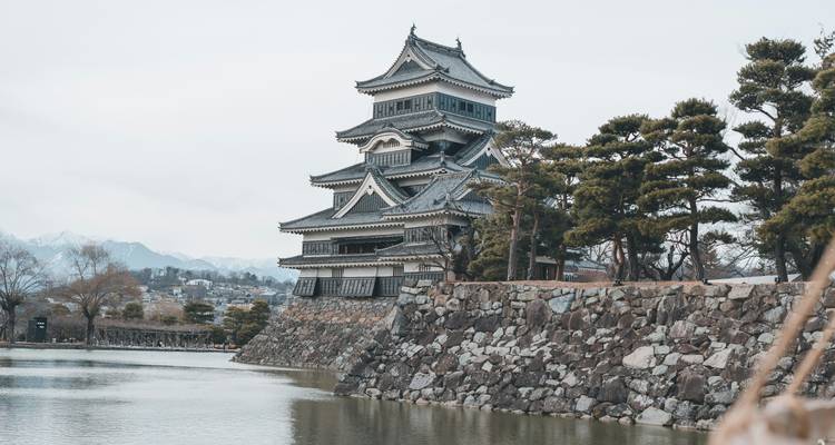Le château de Matsumoto au bord d'un fossé paisible avec un environnement pittoresque.