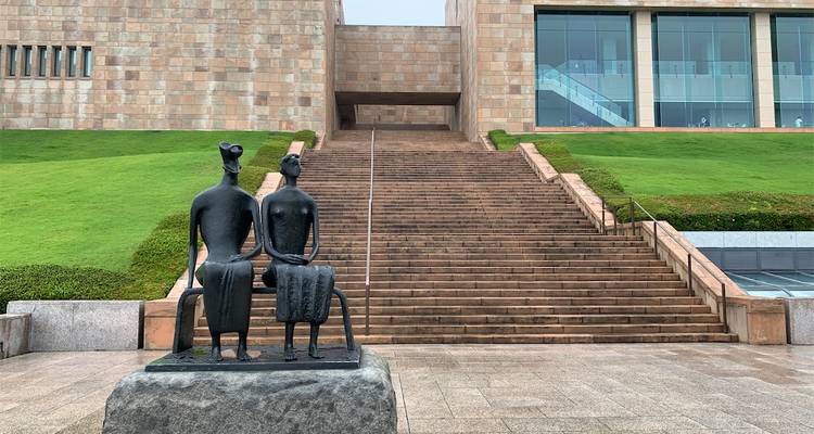 Escalier extérieur menant à un bâtiment moderne avec une sculpture.