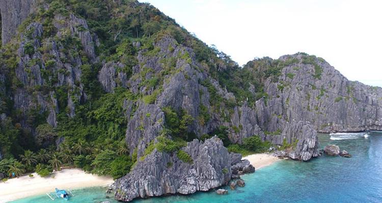 Jagged cliffs meeting the ocean on a sunny day.