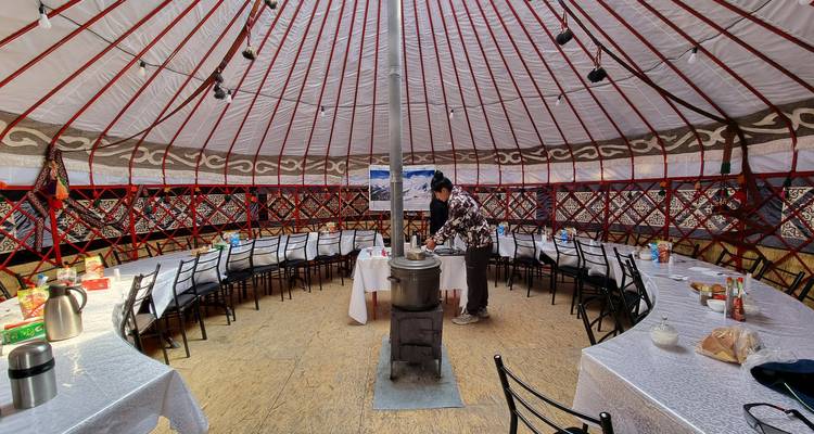 Intérieur d'une yourte avec poêle et tables.