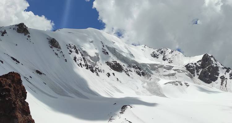 Chaîne de montagnes enneigée avec des nuages projetant des ombres.