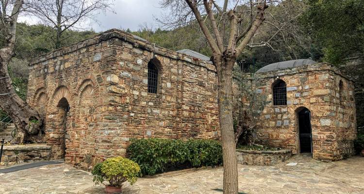 Bâtiment en pierre entouré de verdure dans un cadre ancien.