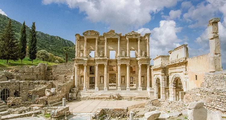 Ruines antiques de bibliothèque en pierre avec ciel nuageux.