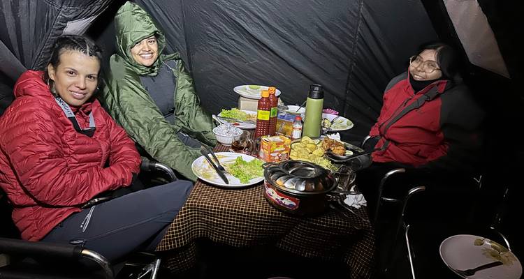 Drie mensen die dineren in een kampeertent.