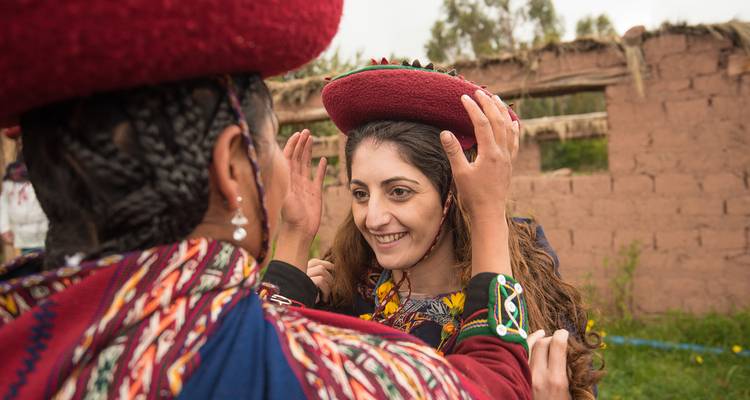 Persona local ayudando a un turista a probarse vestimenta tradicional.