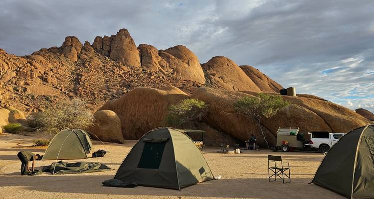 Tentes de camping installées dans un paysage désertique rocheux.