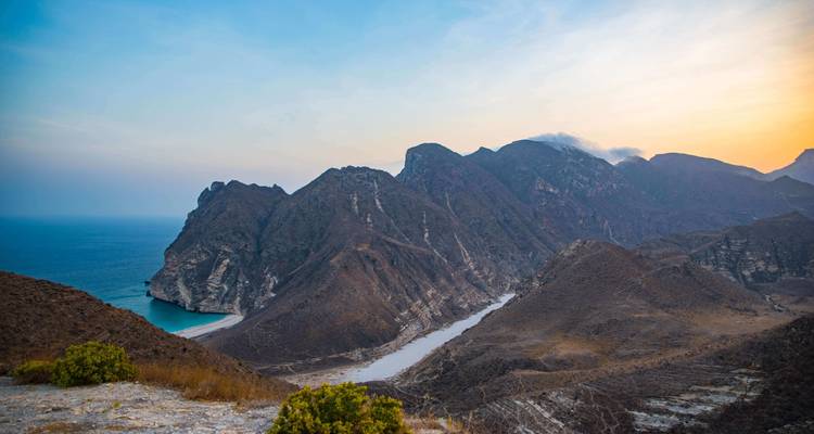Cordillera montañosa con mar al atardecer.