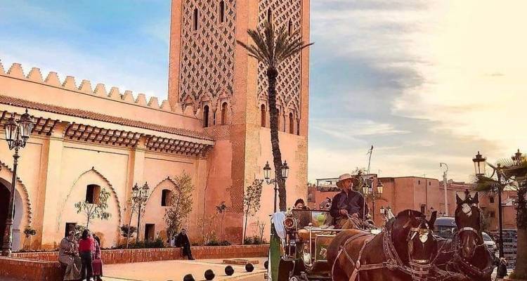 Paardenkoets voor een historische toren bij zonsondergang.