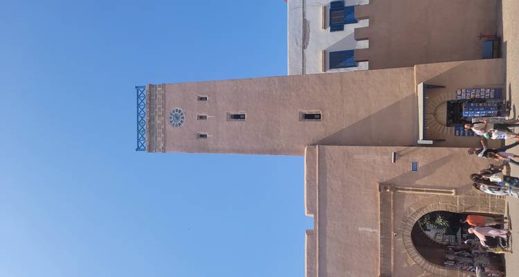Klokkentoren in een historische stad met mensen die voorbijlopen.