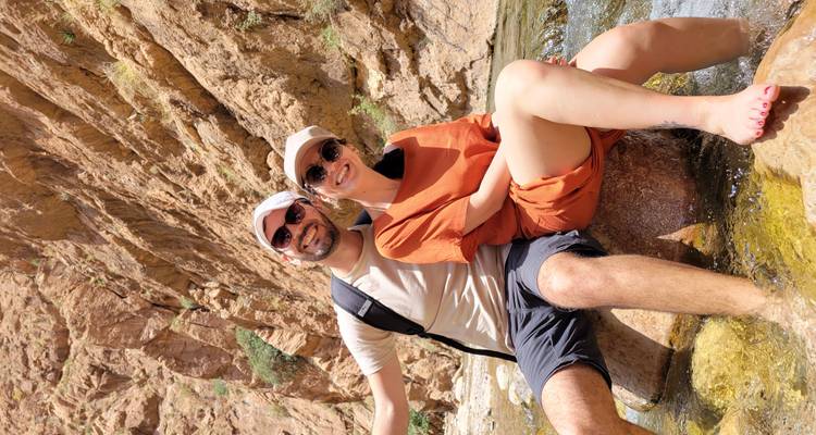Pareja sentada junto a un arroyo en un desfiladero rocoso del desierto.