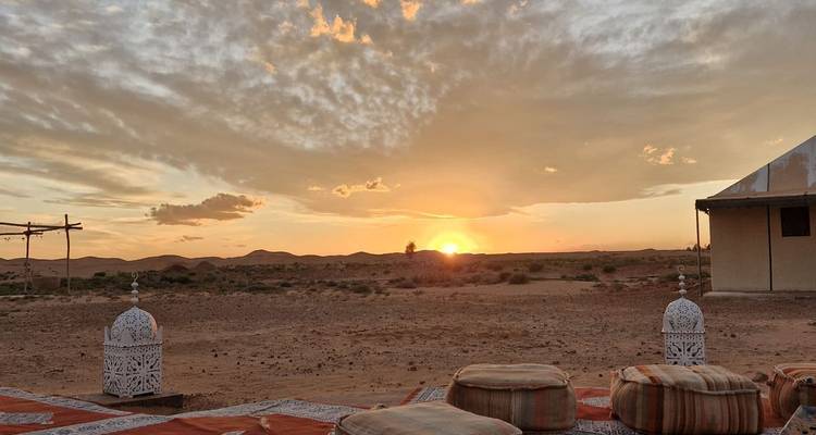 Atardecer sobre un campamento en el desierto con faroles decorativos y cojines