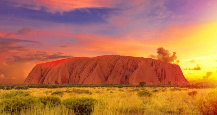 Vibrant sunset or sunrise at Uluru with colorful clouds.