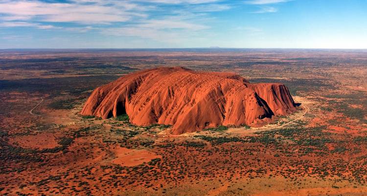 Arial view of Uluru in the surrounding desert landscape.