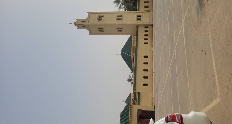 Mosquée avec quelques voitures visibles dans une zone de stationnement vide.