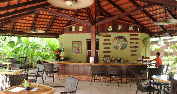 Outdoor cafe with tables in a lush garden setting.