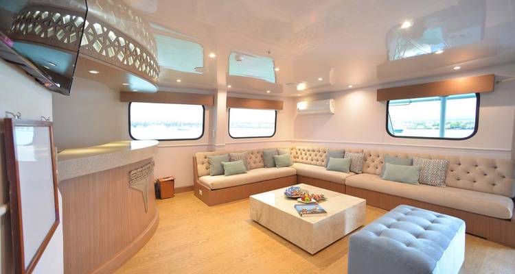 Intérieur d'un salon sur un yacht avec des canapés et une table.