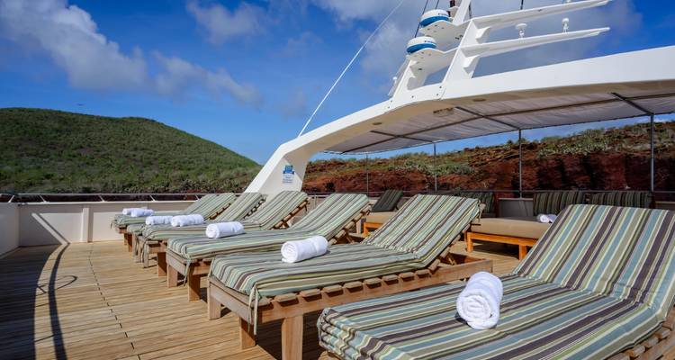 Chaises longues avec des serviettes sur le pont d'un yacht avec vue sur les collines.