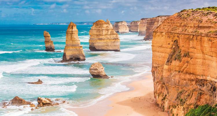 Dramatic coastal cliffs and sea stacks with crashing waves.