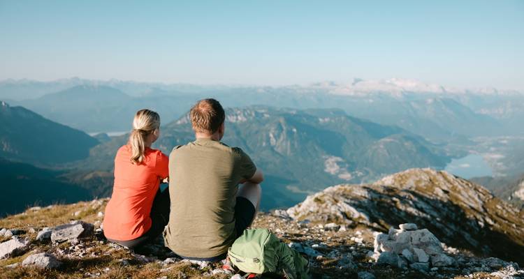 Un couple assis sur un sommet de montagne surplombant un paysage pittoresque.