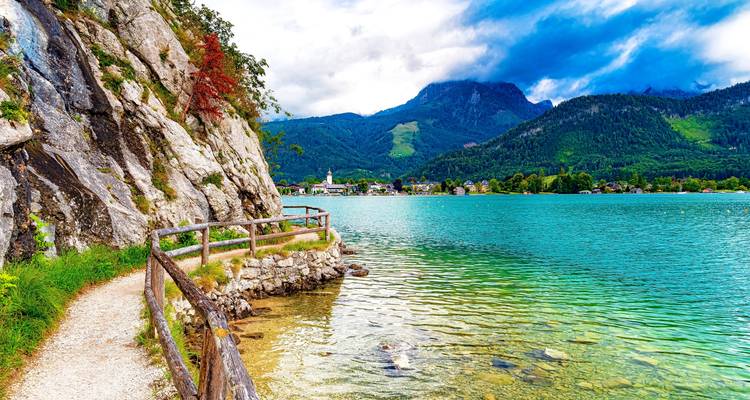 Un lac serein entouré de montagnes et d'un sentier de promenade.