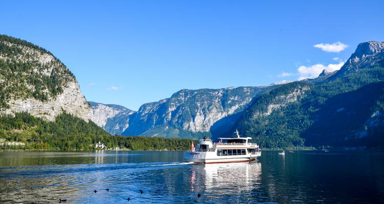 Un lac pittoresque avec un ferry et des montagnes en arrière-plan.