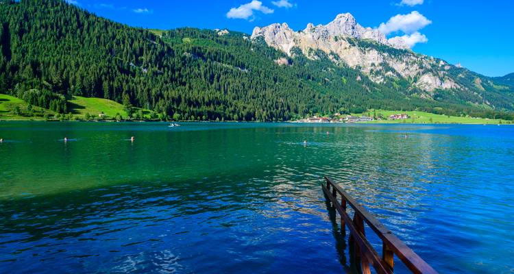 Lac turquoise sur fond de forêt verte et de montagnes.