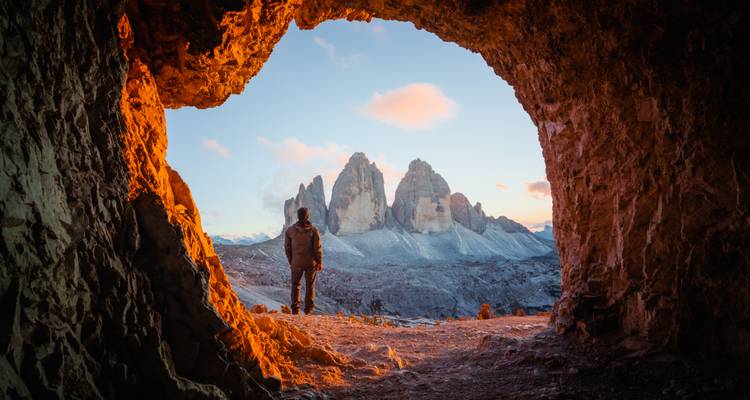 Vue depuis une grotte vers des pics montagneux emblématiques au lever du soleil.