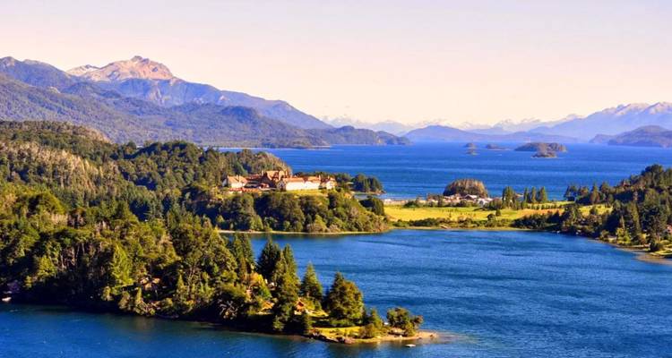 Vue imprenable sur un lac avec une végétation luxuriante et des montagnes au loin.