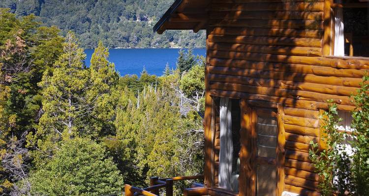 Cabane en bois avec un lac et une forêt en arrière-plan.