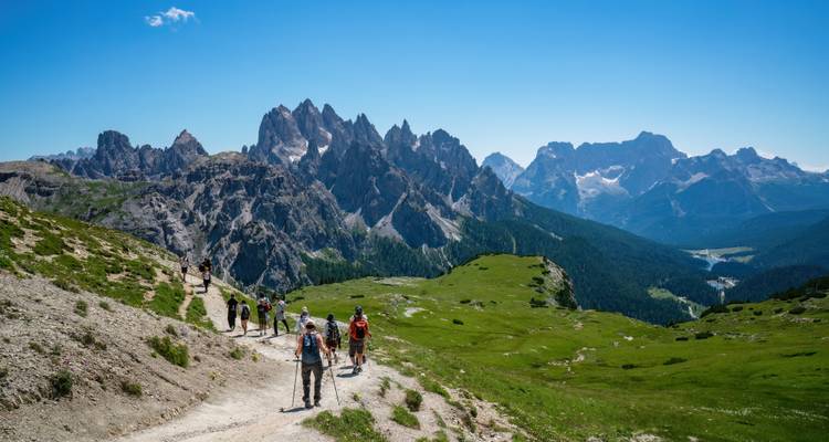 Gruppe von Wanderern, die auf einem Wanderweg in einer bergigen Region gehen.