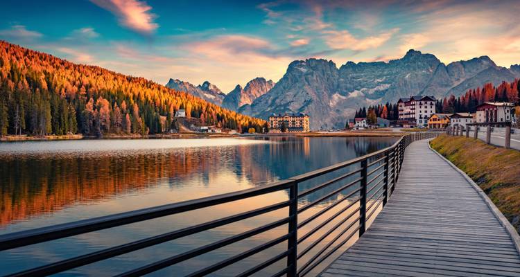Malerischer Blick auf einen See mit Herbstbäumen und Bergen im Hintergrund.