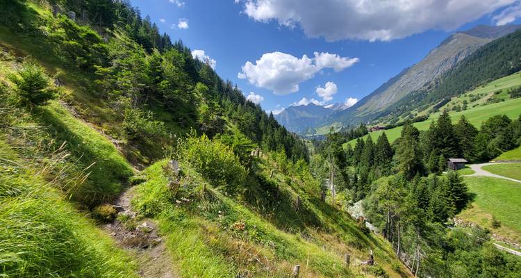 Malerische Aussicht auf eine bergige Landschaft mit grünen Hügeln und blauem Himmel.