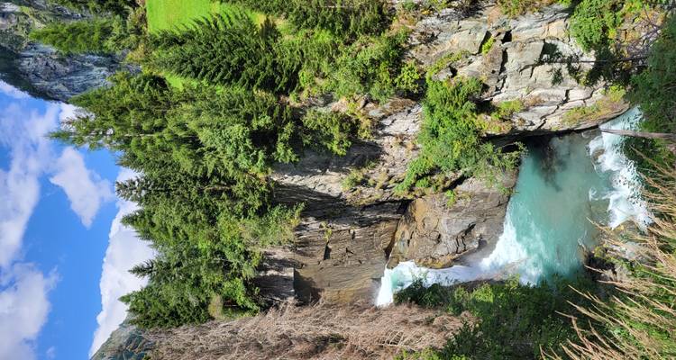 Atemberaubender Wasserfall umgeben von felsigen Klippen und hohen Bäumen.