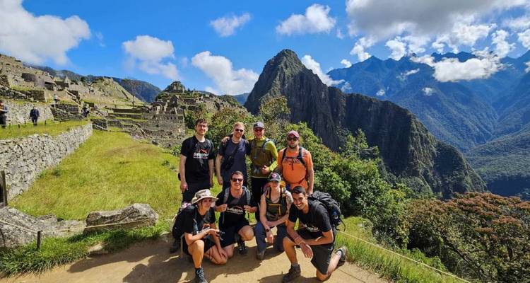 Groupe posant devant le Machu Picchu sous un ciel bleu dégagé.