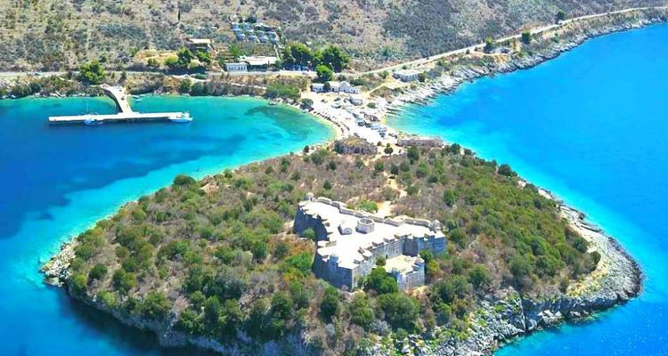 Luftaufnahme einer Küstenfestung umgeben von blauem Wasser.