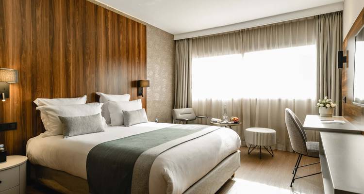 Chambre d'hôtel confortable avec un lit double et lumière du jour.