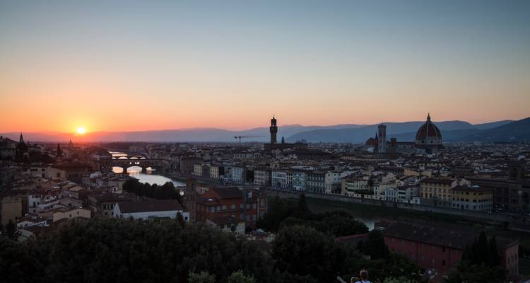 Silhouet van Florance's skyline bij zonsondergang met de zon die achter de heuvels en de Arno-rivier verdwijnt.