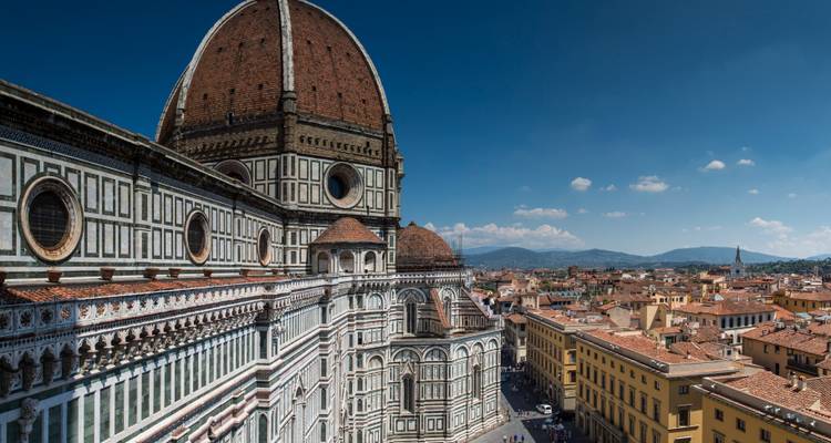 Gedetailleerde gevel en koepel van Florence's Duomo met terracottadaken die zich uitstrekken naar verre heuvels.