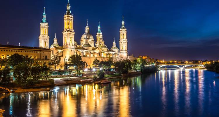 Illuminated cathedral by the river at night.