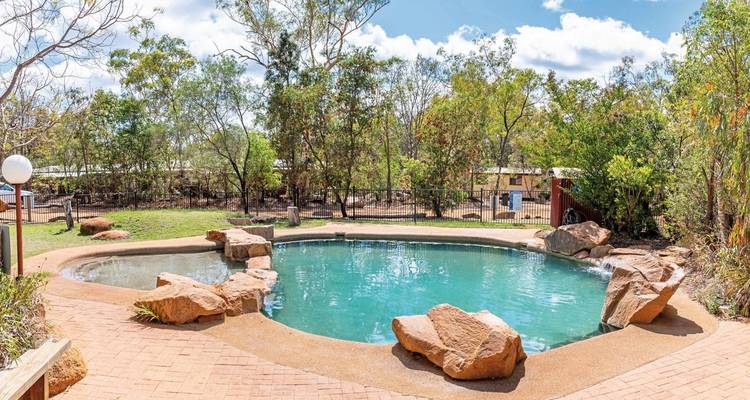 Swimming pool surrounded by trees in a natural setting.